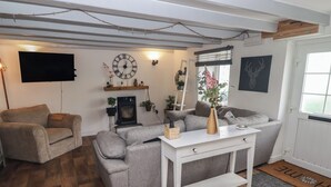 Ein Wohnzimmer mit grauem Sofa, einem weißen Couchtisch, einem Kamin und einer an der Wand befestigten Uhr.