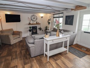 A living room with a grey sofa, a white coffee table, a fireplace, and a wall-mounted clock. - 41 St. James Street (Narberth)