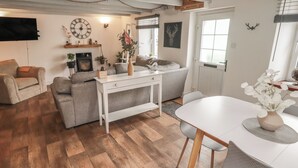 Ein Wohnzimmer mit einer Couch, einem Couchtisch, einem Fernseher und einem Kamin.
