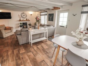 A living room with a sofa, a coffee table, a TV, and a fireplace. - 41 St. James Street (Narberth)