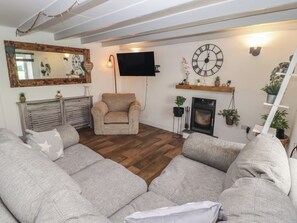 A living room with a sofa set, a fireplace, a television mounted on the wall, and a clock. - 41 St James Street (Narberth)