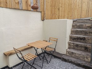 A corner with a wooden table and chairs, a wicker hanging light, and a stone staircase. - 41 St James Street (Narberth)