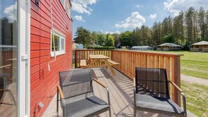 En röd byggnad med en veranda, två stolar och ett bord.