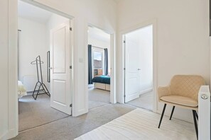 Passadís que condueix a una habitació amb un llit, un radiador i una cadira.