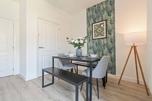 Ein Essbereich mit einem Tisch für zwei Personen, einer Bank und einer Stehlampe.