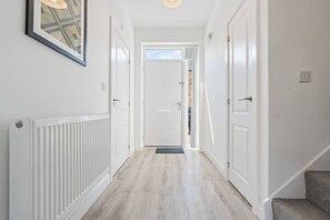 A hallway with a radiator, a framed picture, and a door leading to another room. - #181 Hidden Gem Near Birmingham Centre - Sleeps 6 (Balsall Heath)