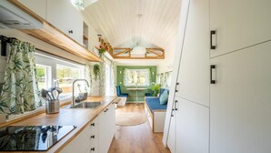 Et kompakt køkken med træbordplade, vask og spiseplads med bænk.