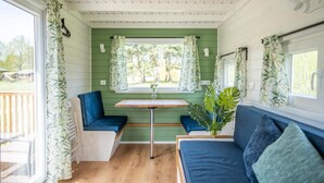 Hyggelig indretning med en træbænk, et bord og et vindue med gardiner.
