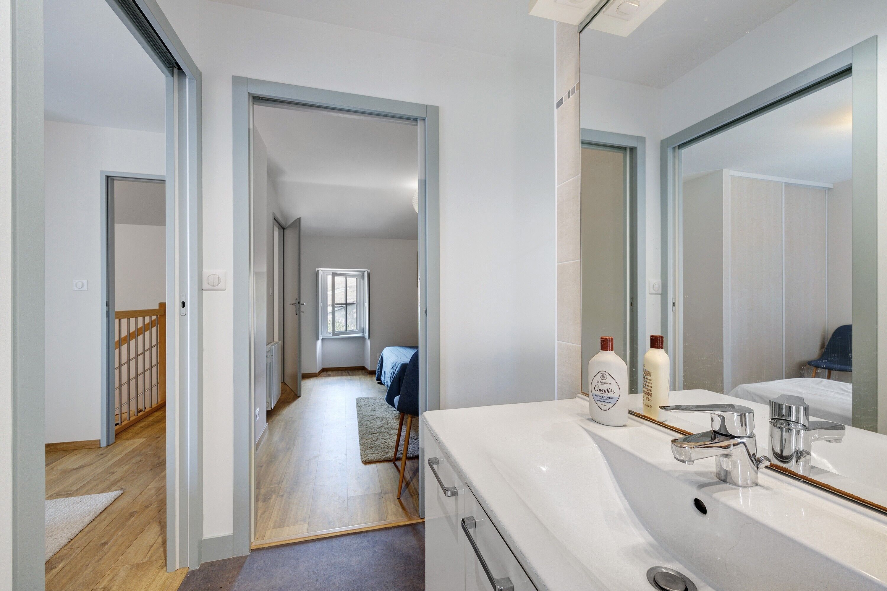 A modern bathroom with a large mirror, a white sink, and toiletries. - Holiday Home 'Maison La Petite Muraillère' with Private Terrace, Private Garden and Wi-Fi (Saint-Étienne-de-Mer-Morte)