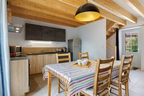 A modern kitchen with wooden cabinets, a built-in microwave, and a stainless steel refrigerator.