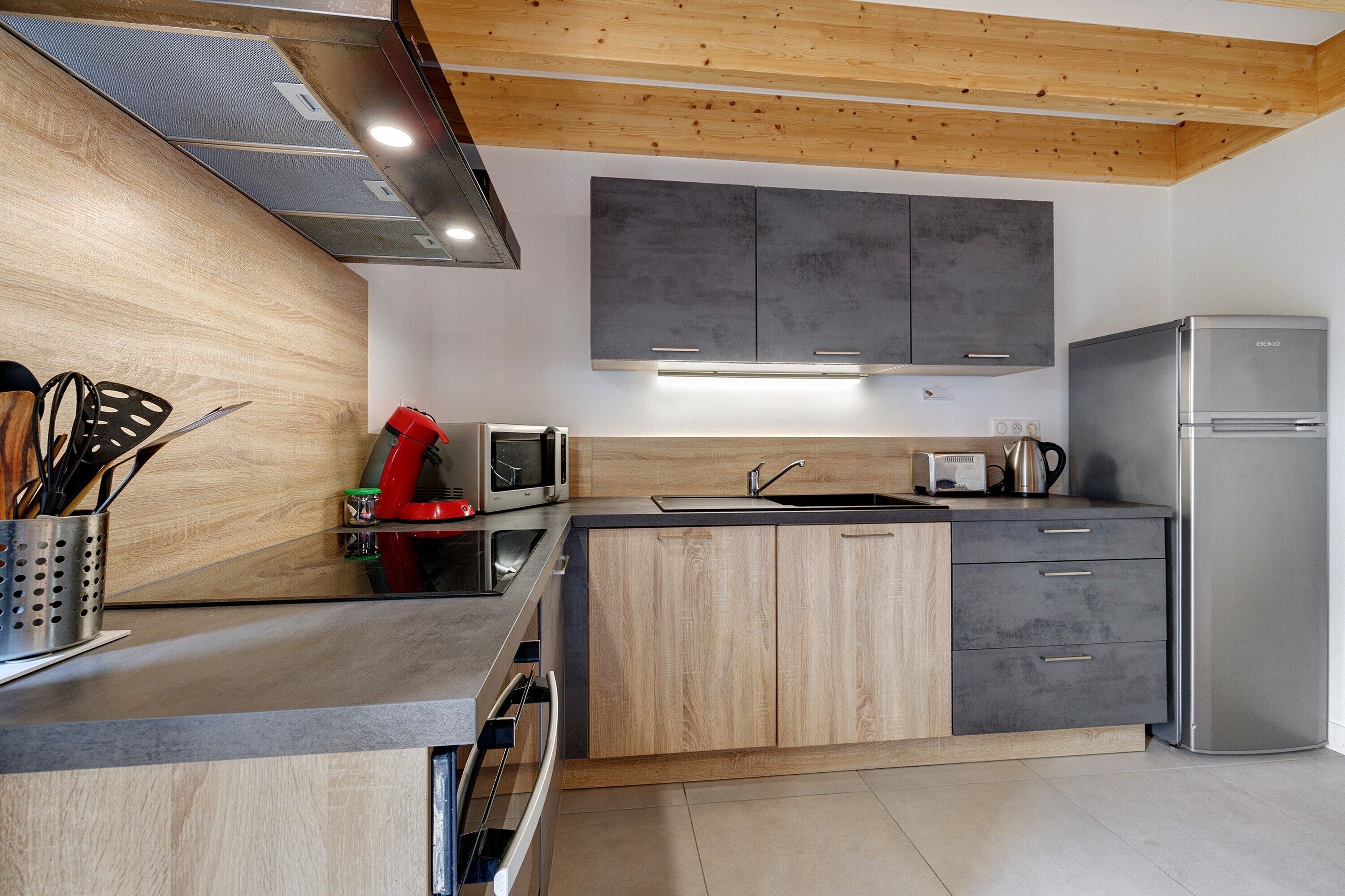 A modern kitchen with wooden cabinets, a stainless steel refrigerator, and a built-in oven.