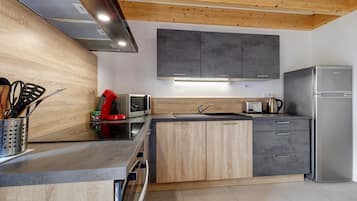 A modern kitchen with wooden cabinets, a stainless steel refrigerator, and a built-in oven.