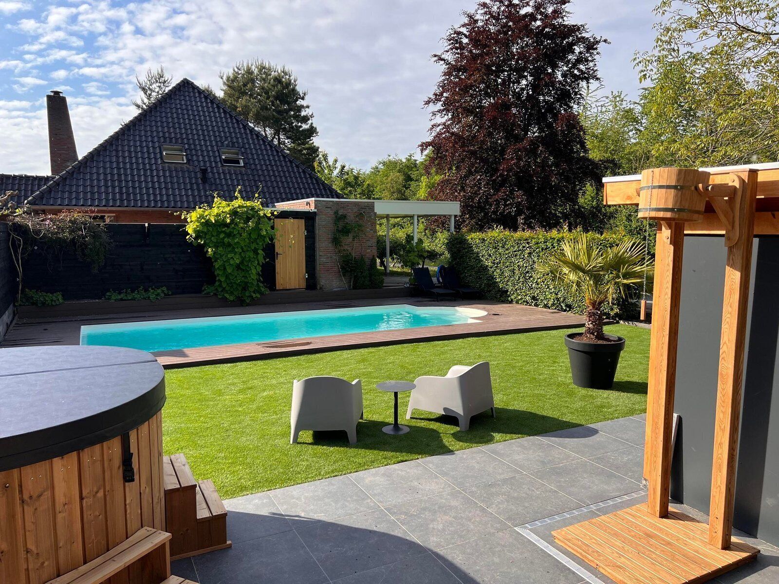 Ein Garten mit Schwimmbad, einer Holzterrasse und einer Pergola.