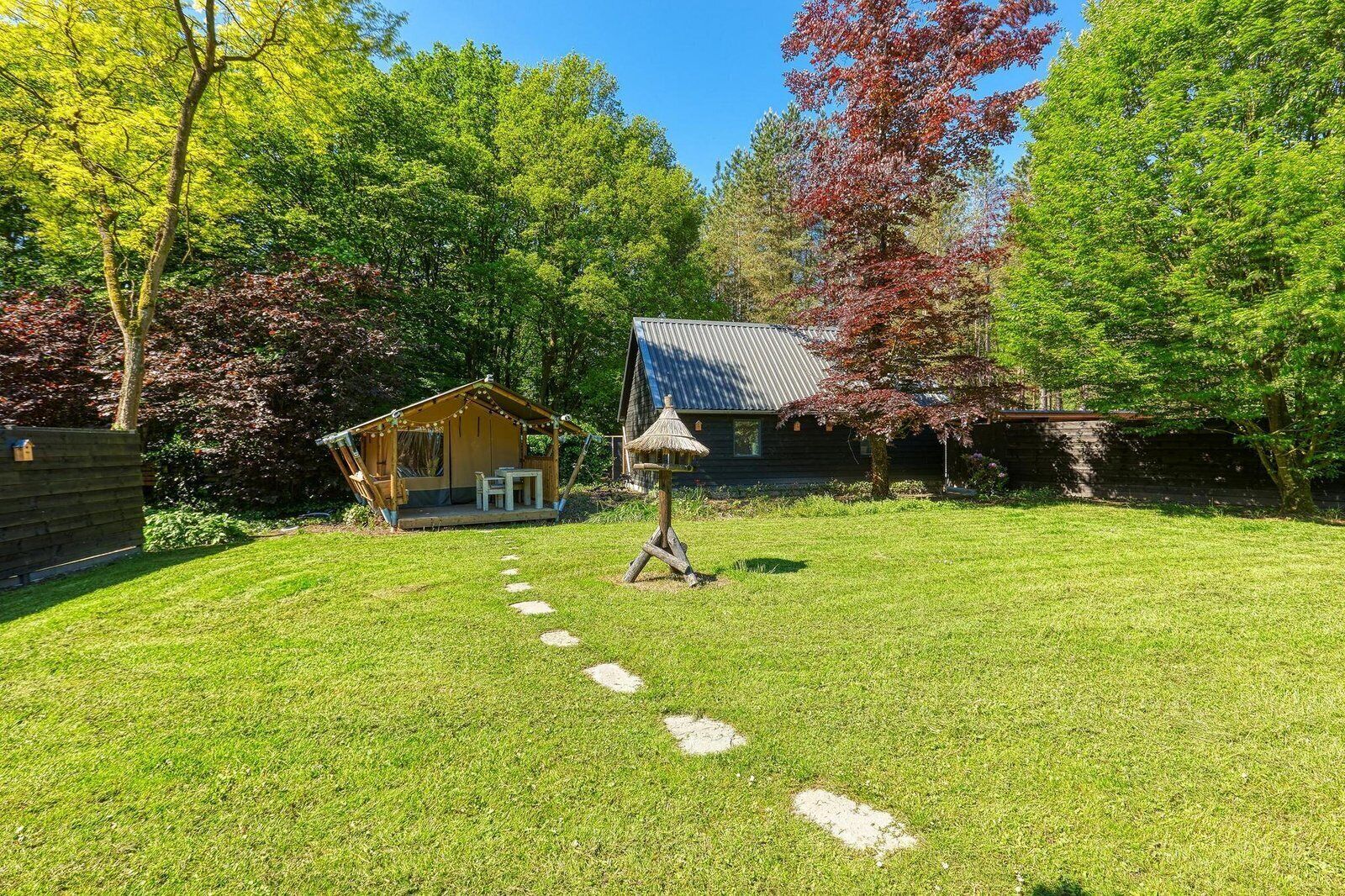 Ein Garten mit einer Holzhütte, einem Gebäude mit Strohdach und einem Kiesweg.
