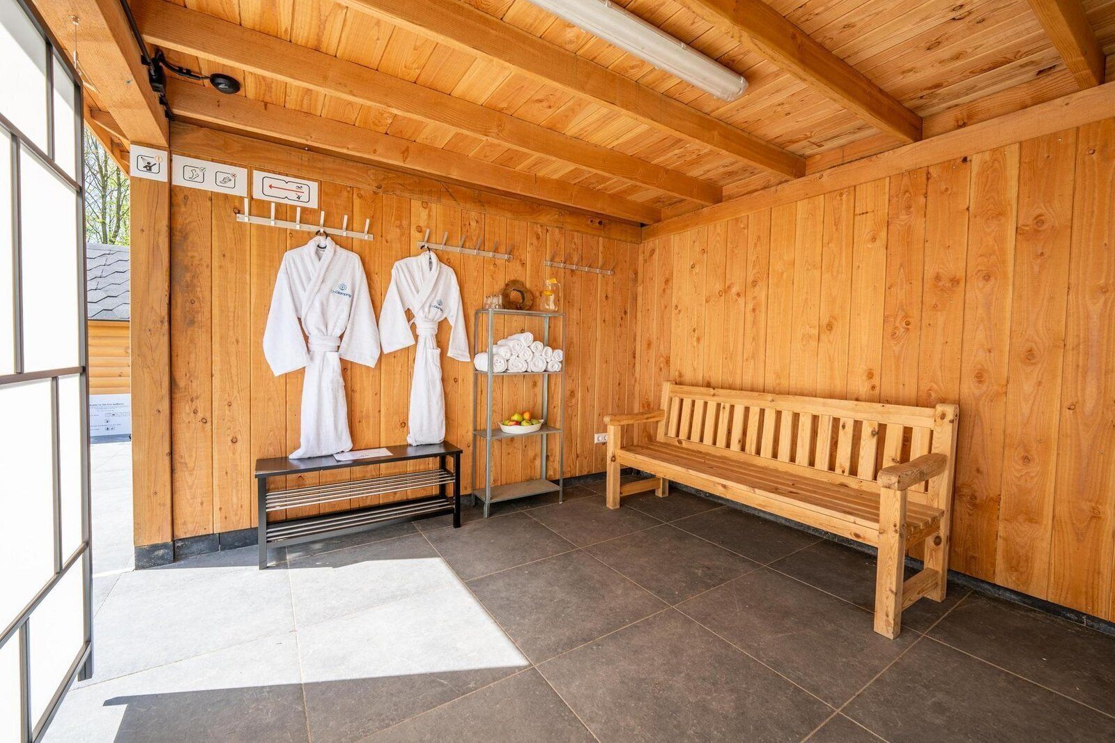 Een houten sauna met banken, handdoeken en een bank met handdoekhouder.