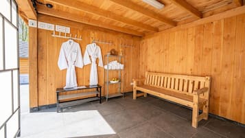 Een houten sauna met banken, handdoeken en een bank met handdoekhouder.