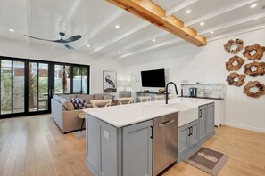 A modern kitchen with a large island, grey cabinets, and a ceiling fan. - Sail Away Estate: 5BDR with Private Pool (Tybee Island)