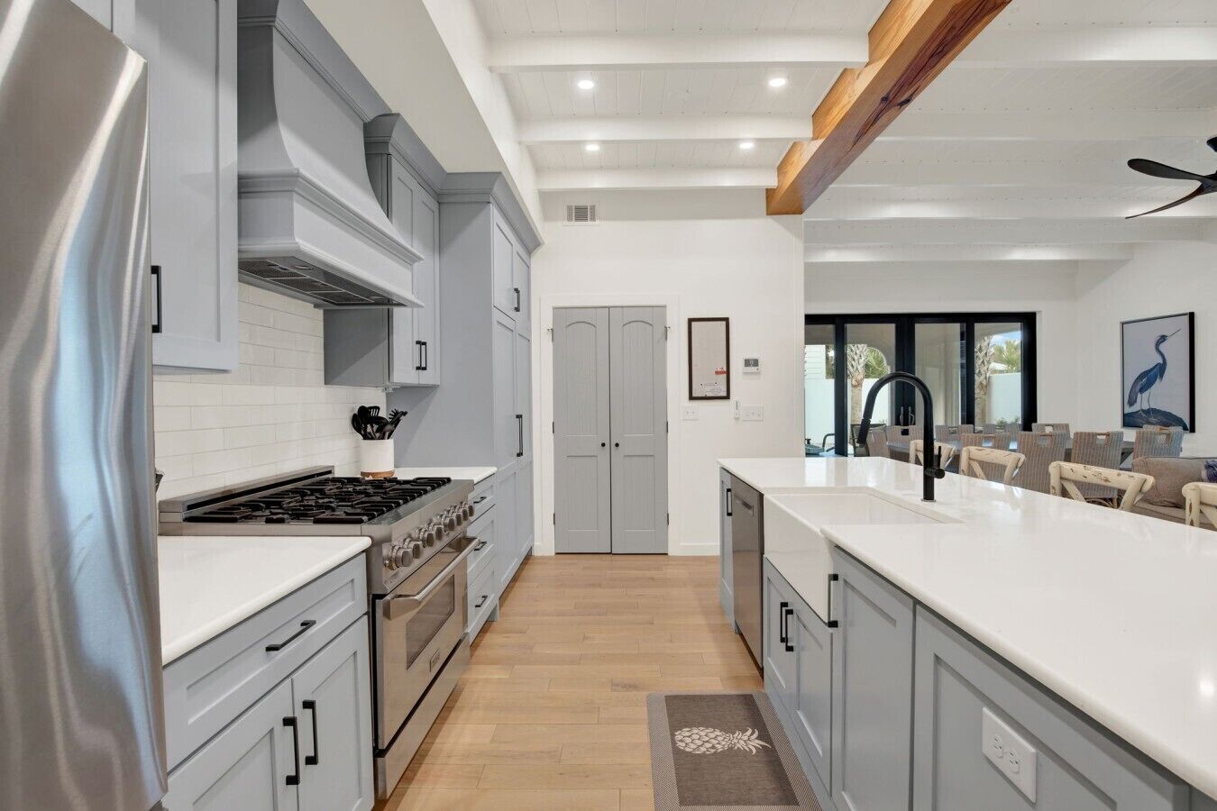 A modern kitchen with a central island, built-in appliances, and a dining area with chairs.