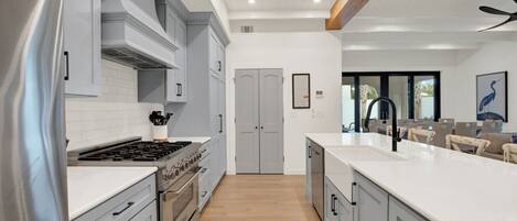 A modern kitchen with a central island, built-in appliances, and a dining area with chairs.