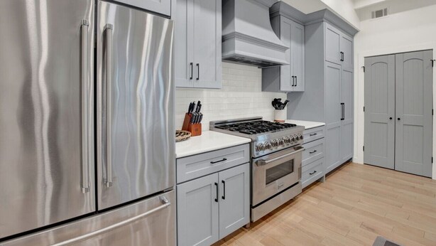 A modern kitchen with stainless steel appliances, grey cabinetry, and a white countertop. - Sail Away Estate: 5BDR with Private Pool (Tybee Island)