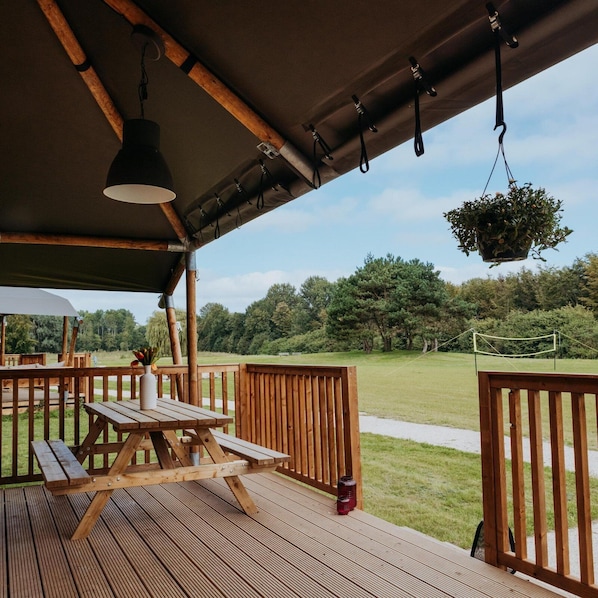 An outdoor wooden deck with a picnic table, hanging lights, and a hanging planter.