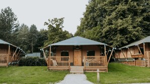 Une rangée de cabanes en bois, dotées d’un porche et d’une entrée couverte, entourées d’arbres.