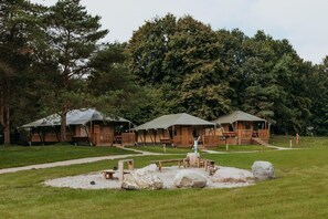 Ein Campingplatz mit Holzhütten, einem Picknicktisch und einer Feuerstelle.