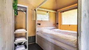 Une pièce de taille modeste, comprenant un lit simple, une petite étagère et une fenêtre.