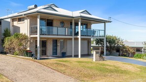 Una casa a due piani con un balcone, un garage e una strada privata.