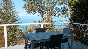 Um terraço com mesa e cadeiras e vista para o litoral.
