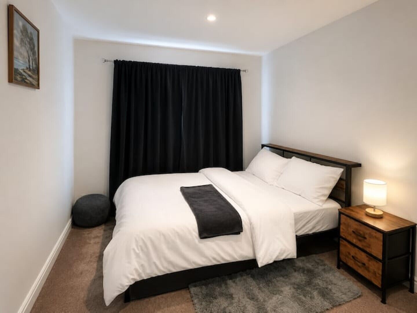 Une chambre à coucher avec un lit, une table de chevet avec une lampe, un tapis rond et un tableau au mur.