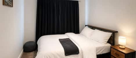 Une chambre à coucher avec un lit, une table de chevet avec une lampe, un tapis rond et un tableau au mur.