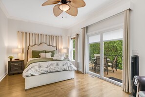 A bedroom with a bed, nightstand, lamp, and a view of an outdoor patio. - Blue Ridge State of Mind | Hot Tub, Fireplace, Dog-Friendly & Biltmore Pass! (Asheville)