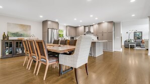 Une cuisine moderne avec un coin repas, un plancher en bois et une grande fenêtre.