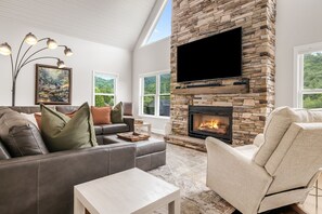 Ein modernes Wohnzimmer mit Kamin aus Stein, Ledersofas und einem Flachbildfernseher.