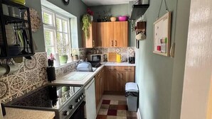 A compact kitchen with wooden cabinets, a gas stove, and a tiled backsplash. - #05 Fam Apart|sleeps 10|near Kingsbury Water Park (Coleshill)