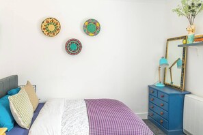 Ein Schlafzimmer mit Bett, Kommode, Spiegel und dekorativen Tellern an der Wand.