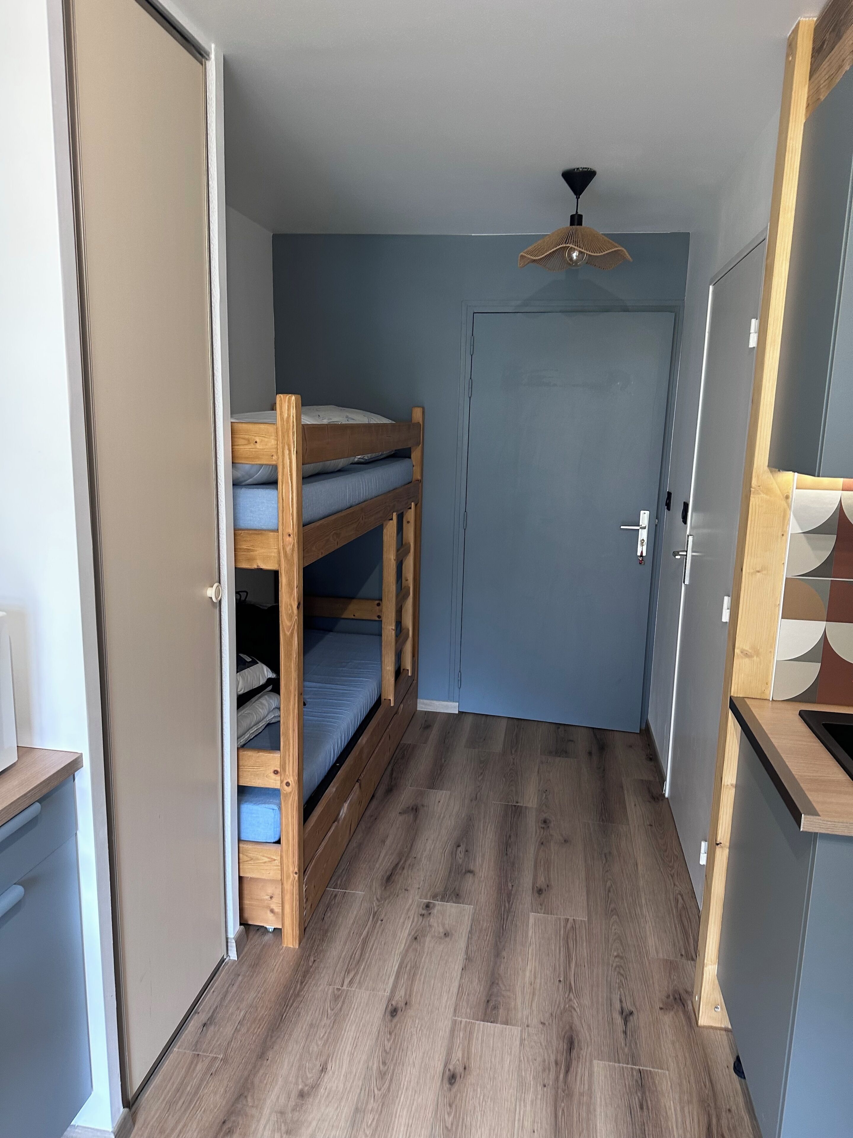 A narrow hallway with a bunk bed, a door, and a ceiling fan.