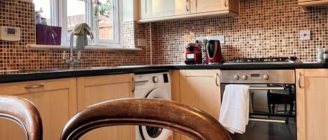 A kitchen with wooden cabinets, a washing machine, an oven, and a window with a view.