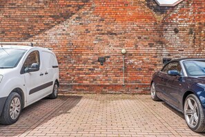 Twee auto's geparkeerd voor een bakstenen muur met een bord dat reserveringsplaatsen aangeeft.
