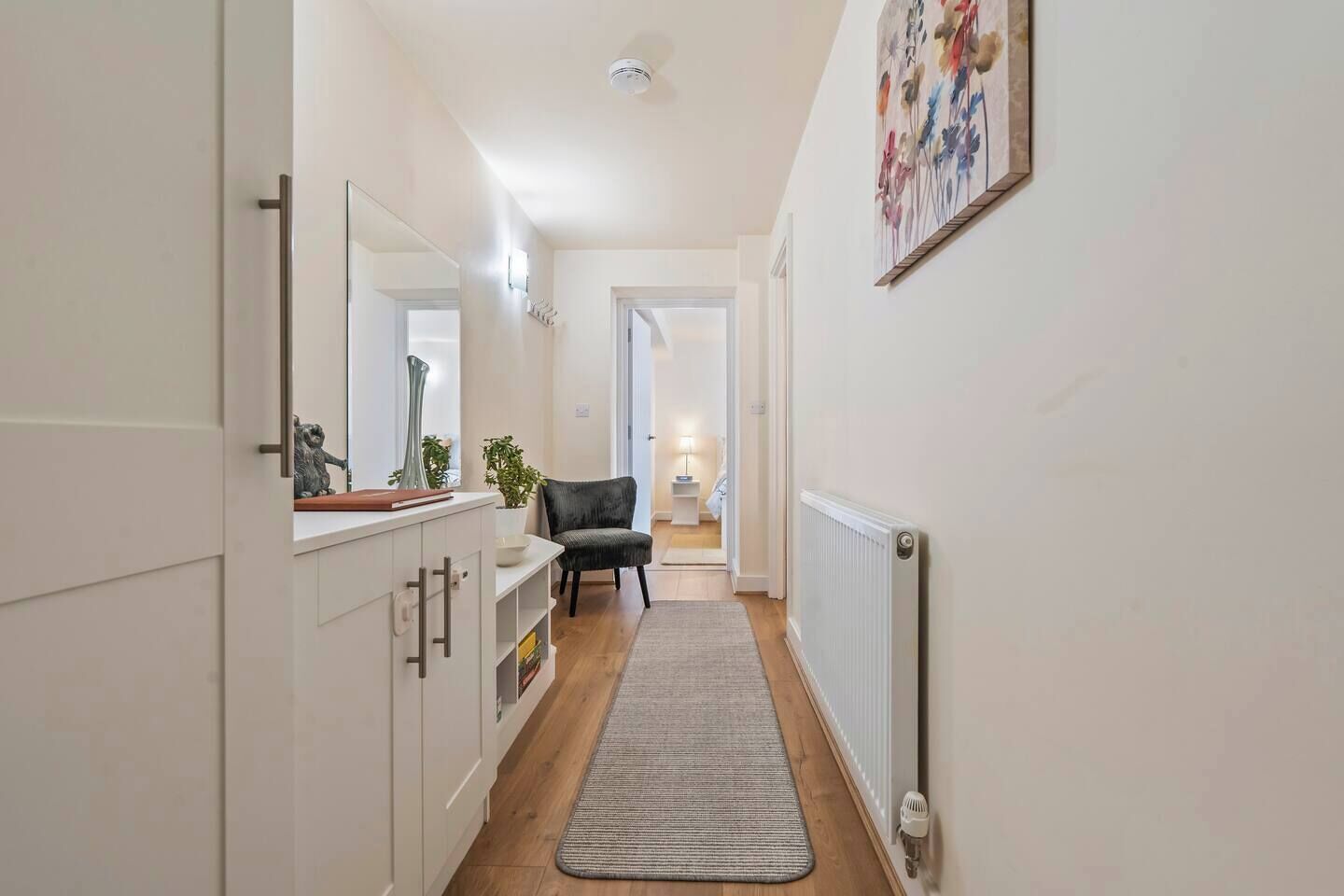 Ein enger Flur mit Heizkörper, Stuhl und Pflanze.