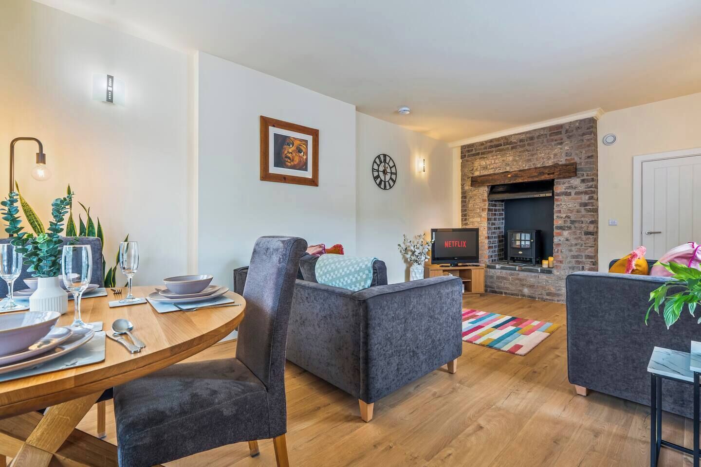 A modern living room with a dining area, a fireplace, and a television displaying 'NETFLIX'.