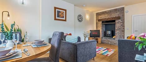 Una sala de estar moderna con comedor, chimenea y televisor mostrando 'NETFLIX'.