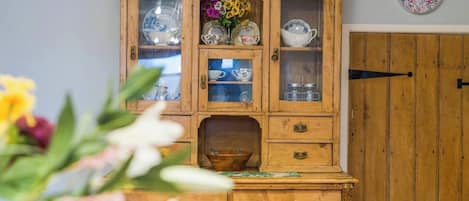 Et træskab med glasdøre, der indeholder tallerkener og en vase med blomster.