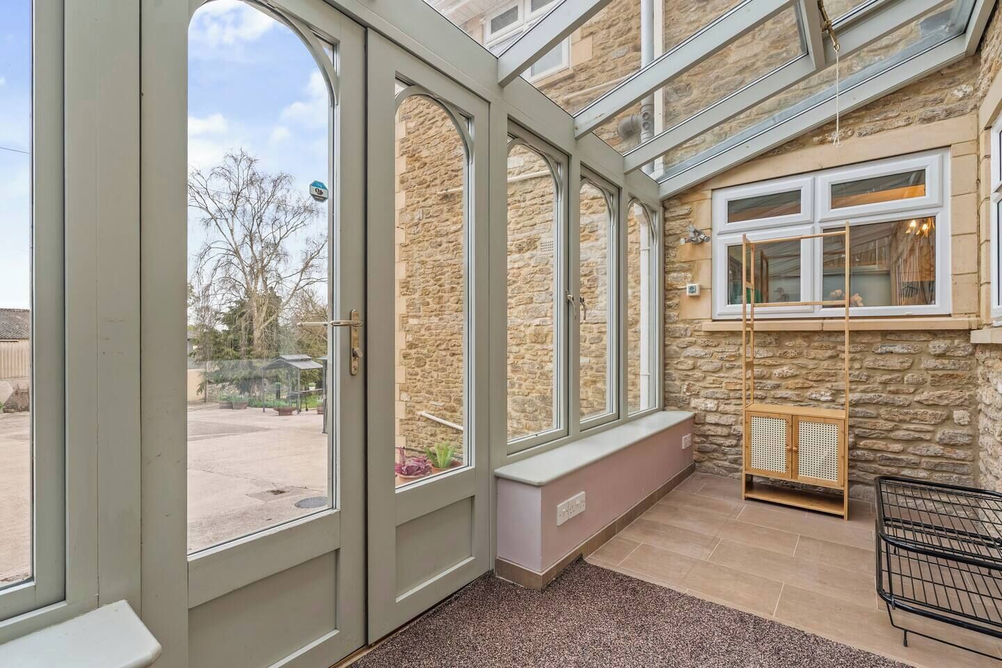 A conservatory with a stone wall, a bench, and a shopping cart.