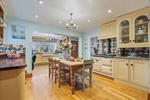 A kitchen with wooden cabinets, a dining table with chairs, and a chandelier. - #110 Charming Country Stay at Brook Farm, Somerset (Whatley)