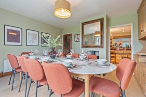 A dining room with a round table set for six, surrounded by six chairs, a large mirror, and framed artwork on the walls. - #110 Charming Country Stay at Brook Farm, Somerset (Whatley)