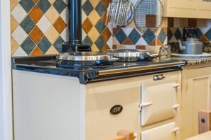 Uma cozinha com fogão, chaleira e painel de azulejos.