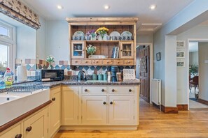 A kitchen with a central island, wooden cabinets, a microwave, and various kitchen appliances. - #110 Charming Country Stay at Brook Farm, Somerset (Whatley)