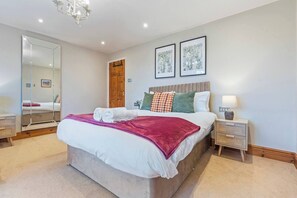 A bedroom with a large bed, a bedside table, a nightstand, a mirror, and two framed pictures on the wall. - #110 Charming Country Stay at Brook Farm, Somerset (Whatley)